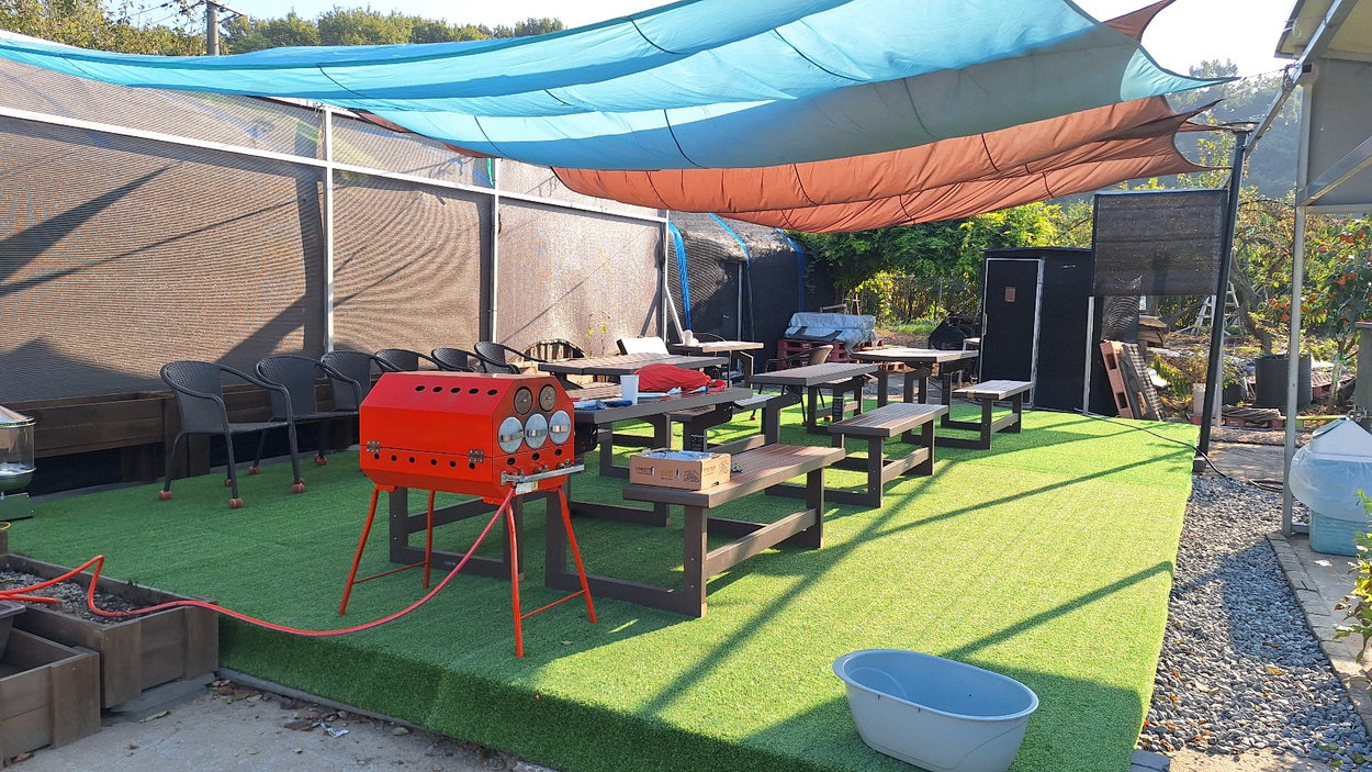 Outdoor farm tables beneath a sunshade
